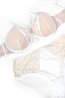 Biustonosz półusztywniony.
Wnętrze miseczki wykonane z beżowej pianki, wierzch z białego plenu, środek zdobi koronka, góra z tiulu. Materiał wyciągnięty ponad miseczkę i połączony z ramiączkiem na kółeczku.
Obwód z podwójnego tiulu, brak bocznej fiszbiny.
Konstrukcja z szerokim łukiem fiszbiny układa biust naturalnie i zapewnia wygodę w całodziennym użytkowaniu.
Skład surowcowy: 85% Poliamid, 10% Elastan, 5% Poliester.
 