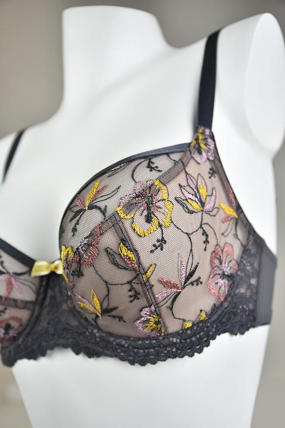 Biustonosz miękki  z fiszbinami.
Miseczki z beżowej siatki, na którą naszyty jest wzorzysty plen-motyw kwiatowy na grafitowym podkładzie.
Boczki z mikrofibry-wzmocnione fiszbiną, grafitowe ramiączka, bawet z koronki, środek zdobi zółta kokardka.
Pewna i sprawdzona konstrukcja z modelu Deziro dedykowana dla średnichi dużych biustów.
Skład surowcowy: 85%Poliamid, 10% Elastan, 5%Poliester.
 