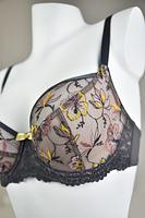 Biustonosz miękki  z fiszbinami.
Miseczki z beżowej siatki, na którą naszyty jest wzorzysty plen-motyw kwiatowy na grafitowym podkładzie.
Boczki z mikrofibry-wzmocnione fiszbiną, grafitowe ramiączka, bawet z koronki, środek zdobi zółta kokardka.
Pewna i sprawdzona konstrukcja z modelu Deziro dedykowana dla średnichi dużych biustów.
Skład surowcowy: 85%Poliamid, 10% Elastan, 5%Poliester.
 