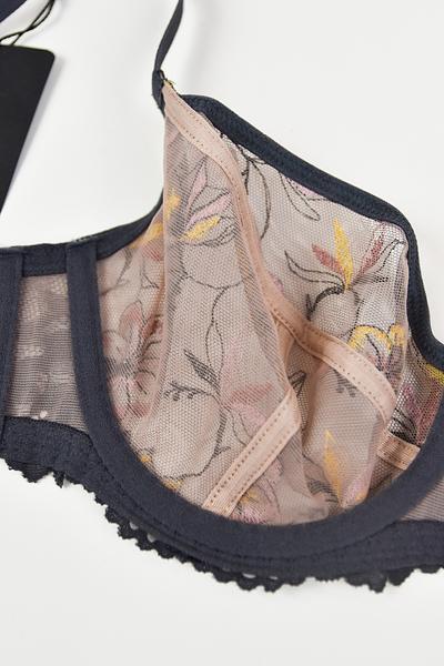 Biustonosz miękki  z fiszbinami.
Miseczki z beżowej siatki, na którą naszyty jest wzorzysty plen-motyw kwiatowy na grafitowym podkładzie.
Boczki z mikrofibry-wzmocnione fiszbiną, grafitowe ramiączka, bawet z koronki, środek zdobi zółta kokardka.
Pewna i sprawdzona konstrukcja z modelu Deziro dedykowana dla średnichi dużych biustów.
Skład surowcowy: 85%Poliamid, 10% Elastan, 5%Poliester.
 